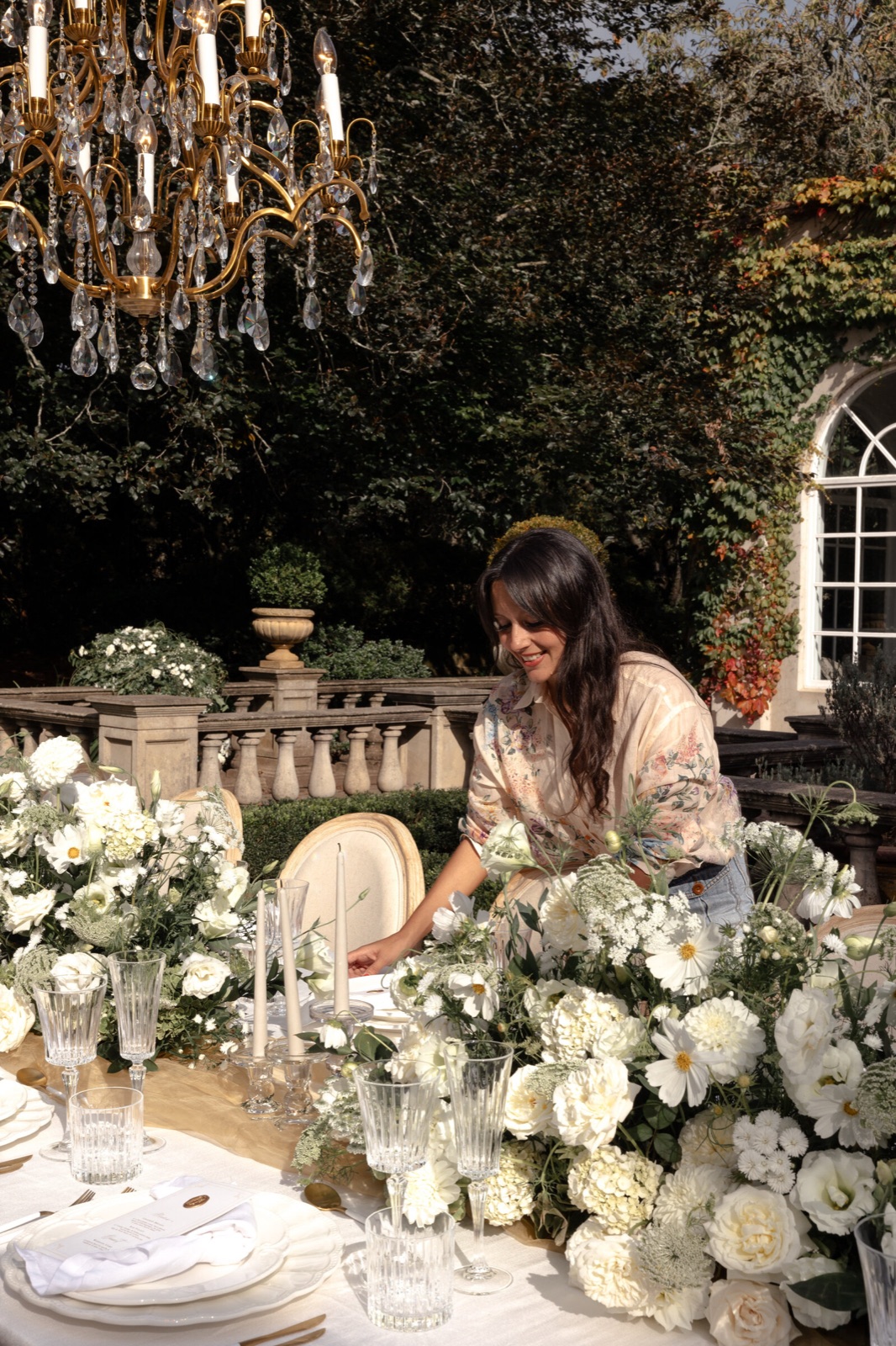 Stefanie styling a reception table under a chandelier